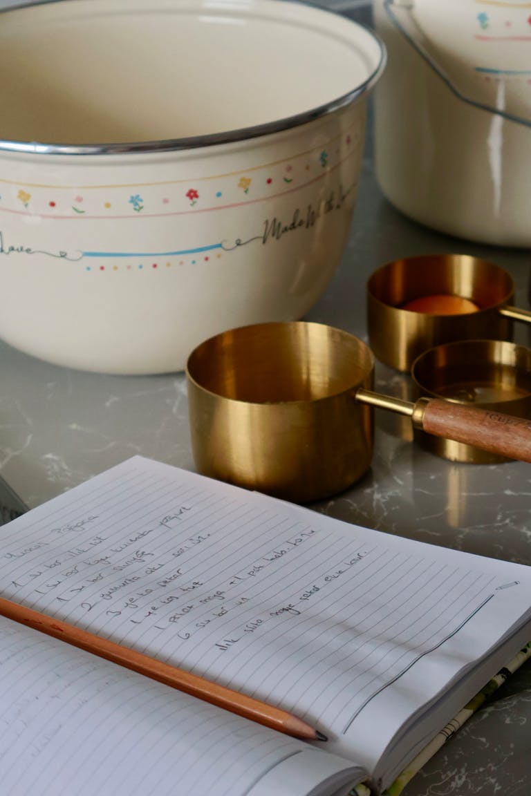 A cozy kitchen setup with a recipe notebook, measuring cups, and mixing bowls.